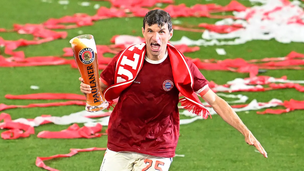 Thomas Müller läuft mit dem Bier in der Hand über den Rasen.