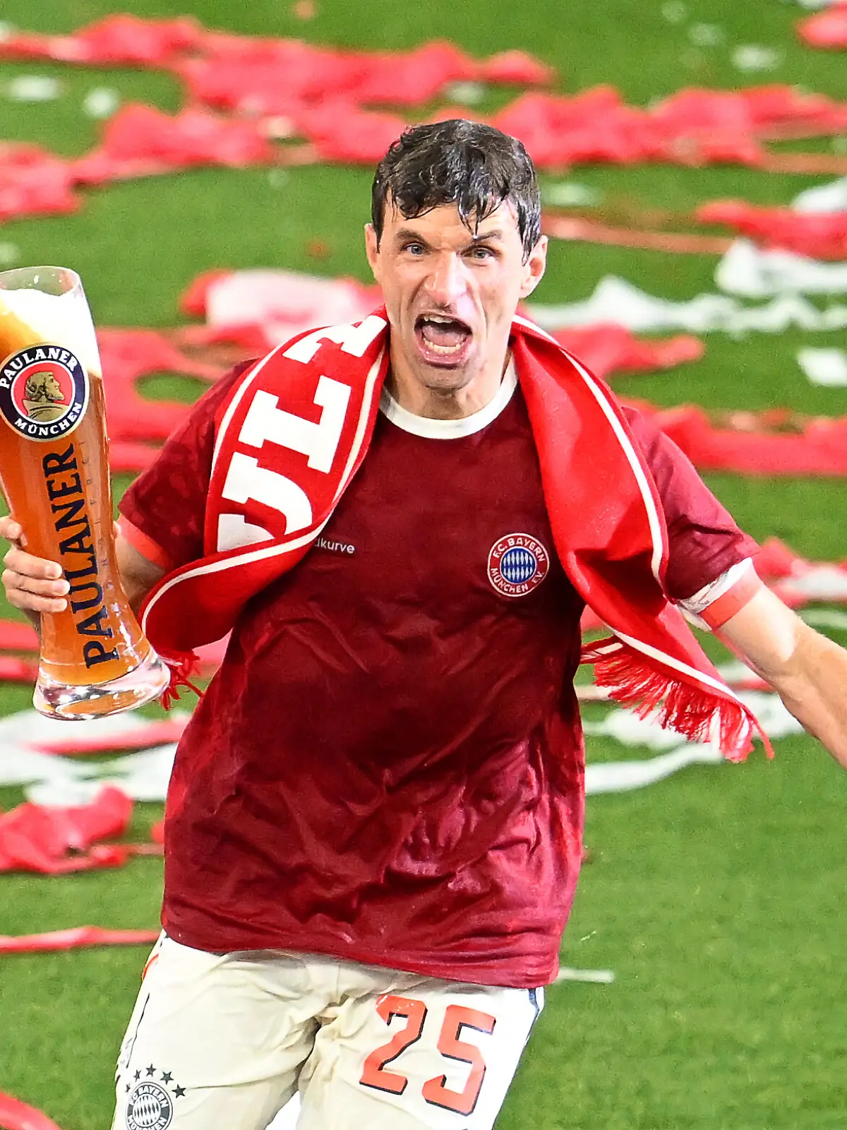 Thomas Müller läuft mit dem Bier in der Hand über den Rasen.