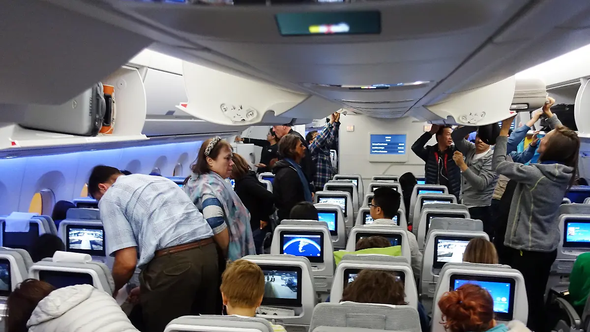 Menschen im Flugzeug holen ihr Handgepäck aus den Deckenfächern.