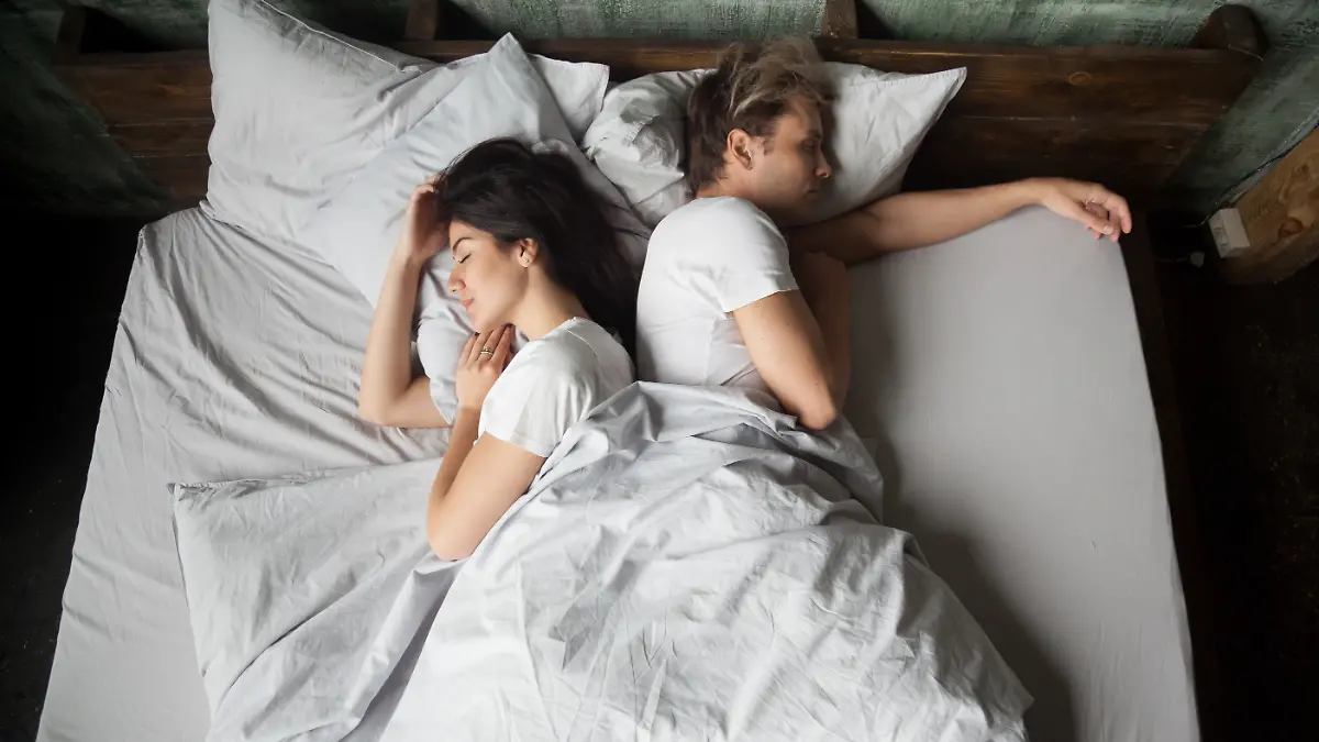 Frau und Mann liegen voneinander abgewandt im Bett und schlafen.