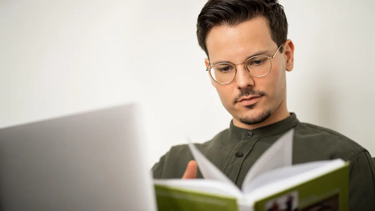 Vegan-Koch Niko Rittenau liest ein Buch vor einem Tisch