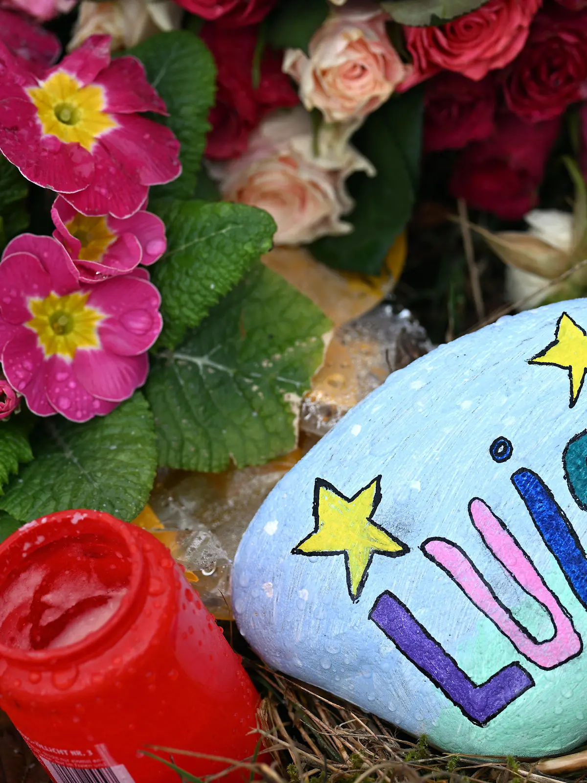 22.03.2023, Nordrhein-Westfalen, Freudenberg: Blumen, Kerzen und ein bunt bemalter und mit "Luise" beschriebener Stein liegen am Tatort. Mit einer Trauerfeier nehmen Angehörige der getöteten zwölfjährigen Luise aus Freudenberg im Siegerland Abschied von dem Mädchen. Der gewaltsame Tod der Zwölfjährigen am 11. März hat viele Menschen geschockt. Zwei 12 und 13 Jahre alte Mädchen hatten gestanden, Luise mit Messerstichen getötet zu haben. Foto: Federico Gambarini/dpa +++ dpa-Bildfunk +++