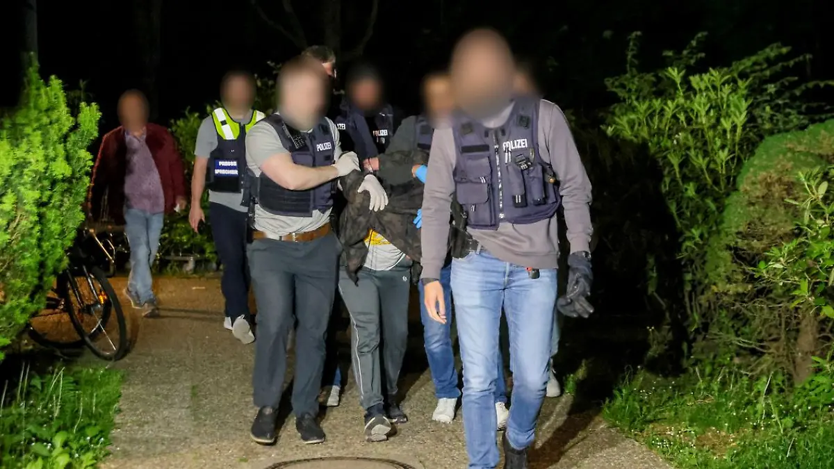 19.05.2025, Nordrhein-Westfalen, Heiligenhaus: Einsatzkräfte der Polizei führen einen Tatverdächtigen nach seiner Festnahme ab. Nach dem Angriff eines Mannes auf mindestens fünf Menschen in Bielefeld ist ein Tatverdächtiger in Heiligenhaus bei Düsseldorf festgenommen worden.