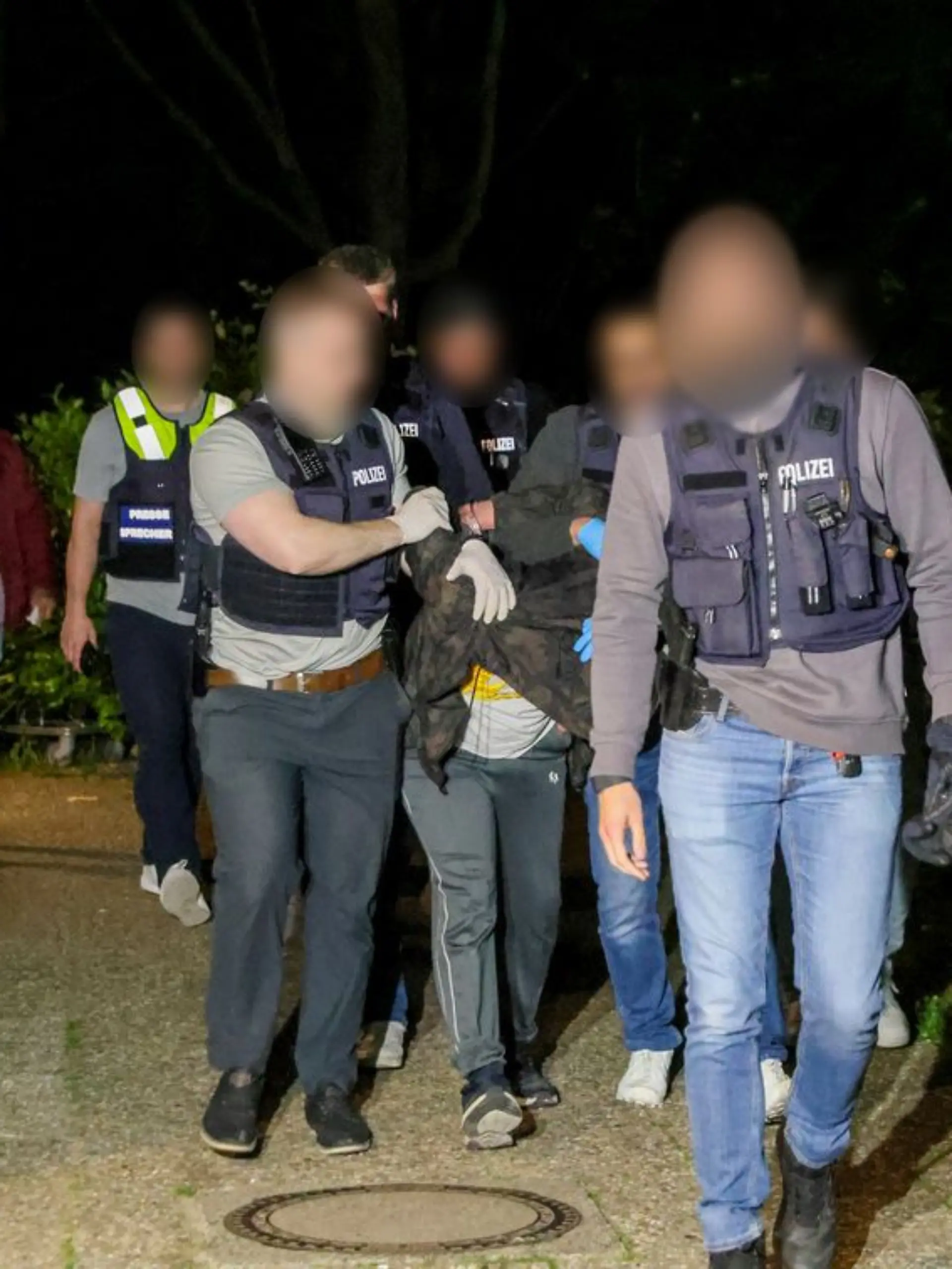 19.05.2025, Nordrhein-Westfalen, Heiligenhaus: Einsatzkräfte der Polizei führen einen Tatverdächtigen nach seiner Festnahme ab. Nach dem Angriff eines Mannes auf mindestens fünf Menschen in Bielefeld ist ein Tatverdächtiger in Heiligenhaus bei Düsseldorf festgenommen worden.