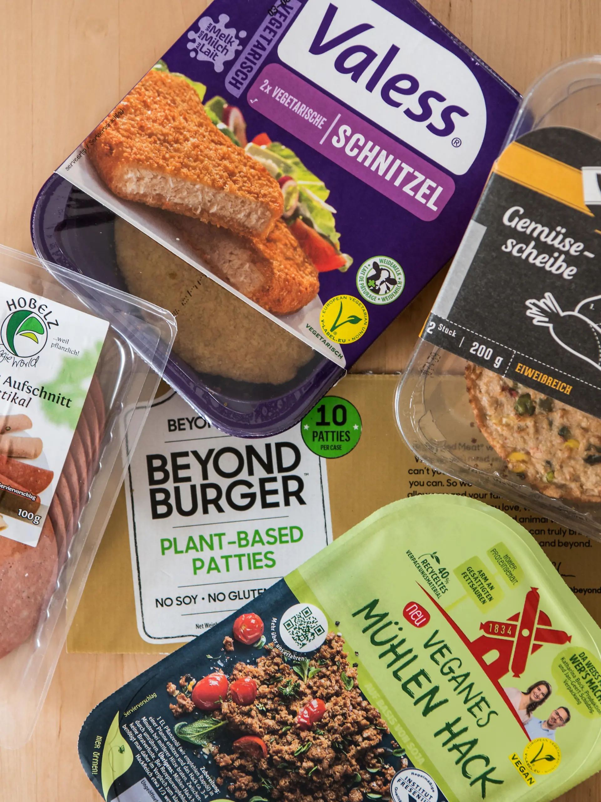 Verschiedene vegane und vegetarische Fleischersatzprodukte liegen verpackt auf dem Tisch. Immer mehr Fleischersatzprodukte kommen auf den deutschen Markt. Die Ersatzprodukte bestehen unter anderem aus Getreide, Soja, Pilzen, Bohnen, Erbsen oder auch der Jackfrucht. (zu dpa "Fleischersatz für das Gewohnheitstier Mensch - Hype um Pflanzenburger"