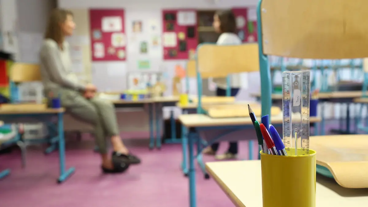 Lehrerin sitzt in leerem Klassenzimmer