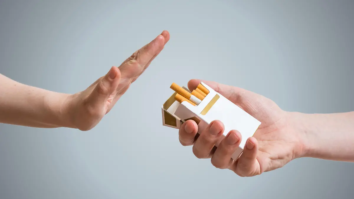 Man sieht zwei Hände vor einem grauen Hintergrund, die eine hält eine Packung Zigaretten in der Hand, die andere macht eine eindeutige Geste, diese abzulehnen.
