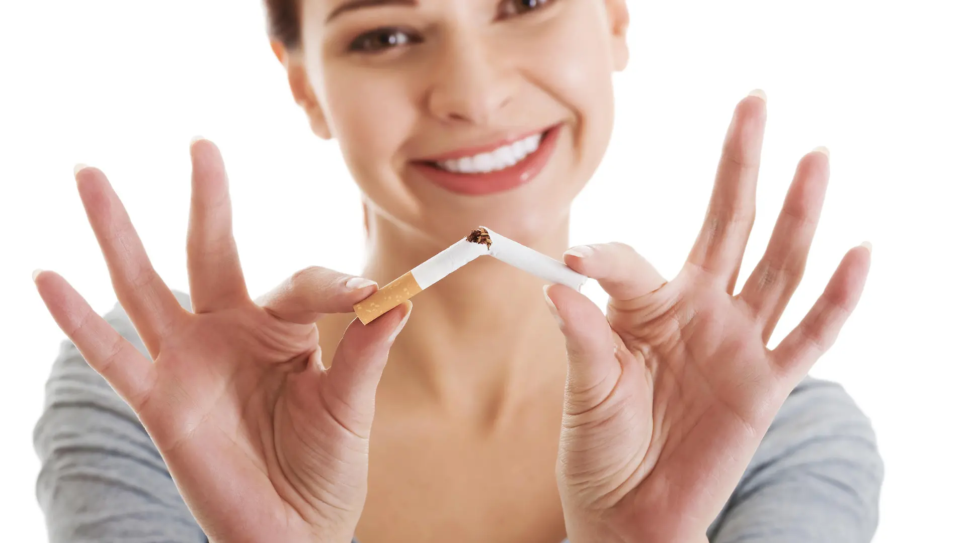 Young beautiful woman holding broken cigarette in front. Isolated on white.