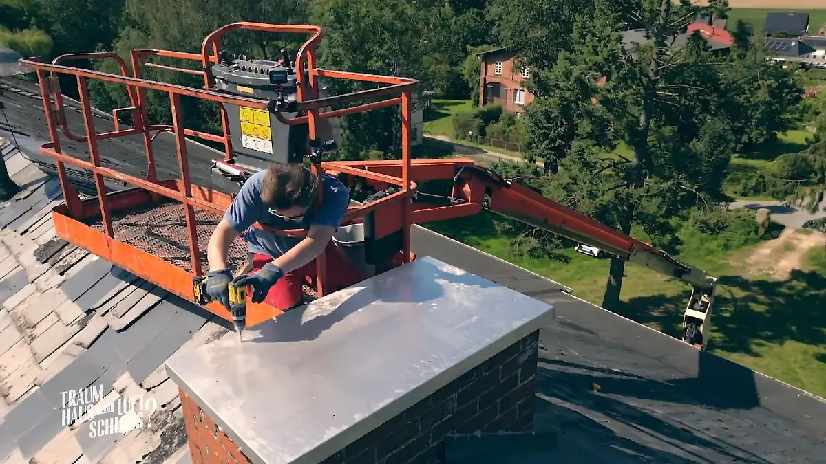 Sönke bringt eine Abdeckung am Schornstein an Herrenhaus
