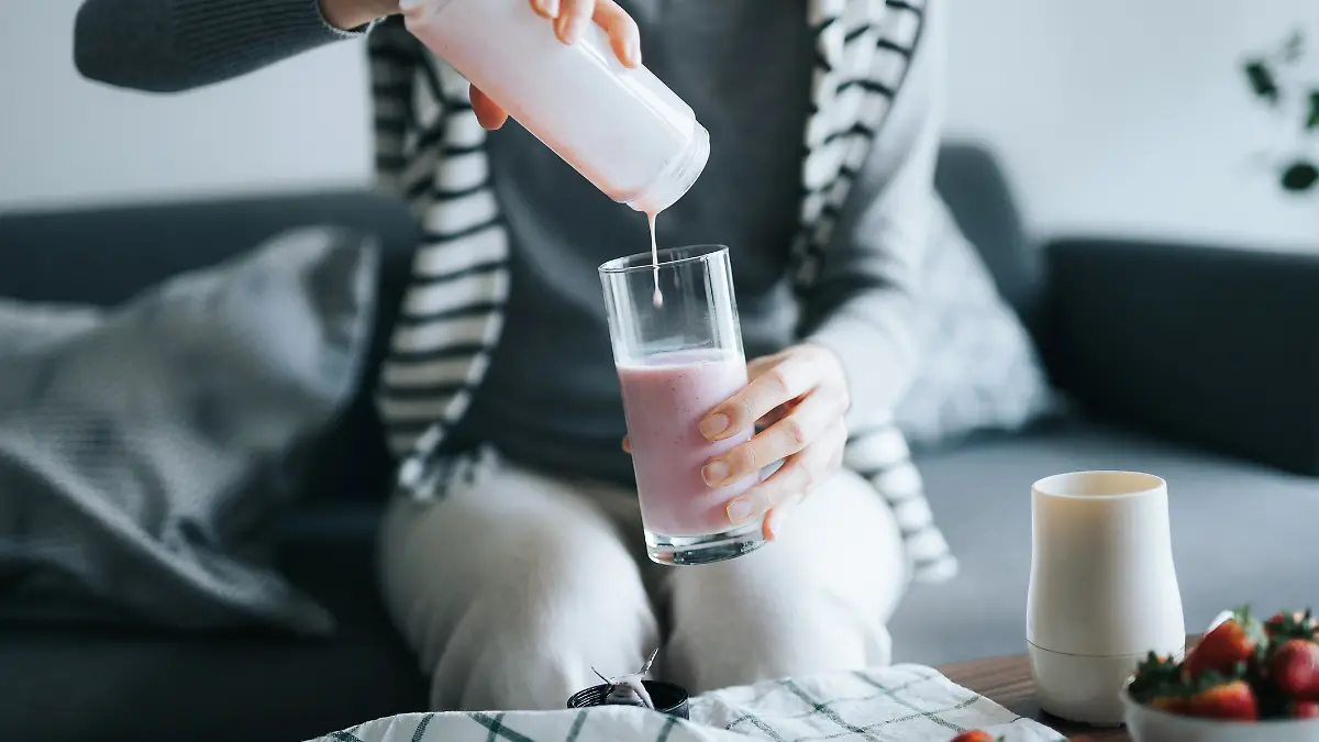 Person gießt sich einen Shake in ein Glas ein.