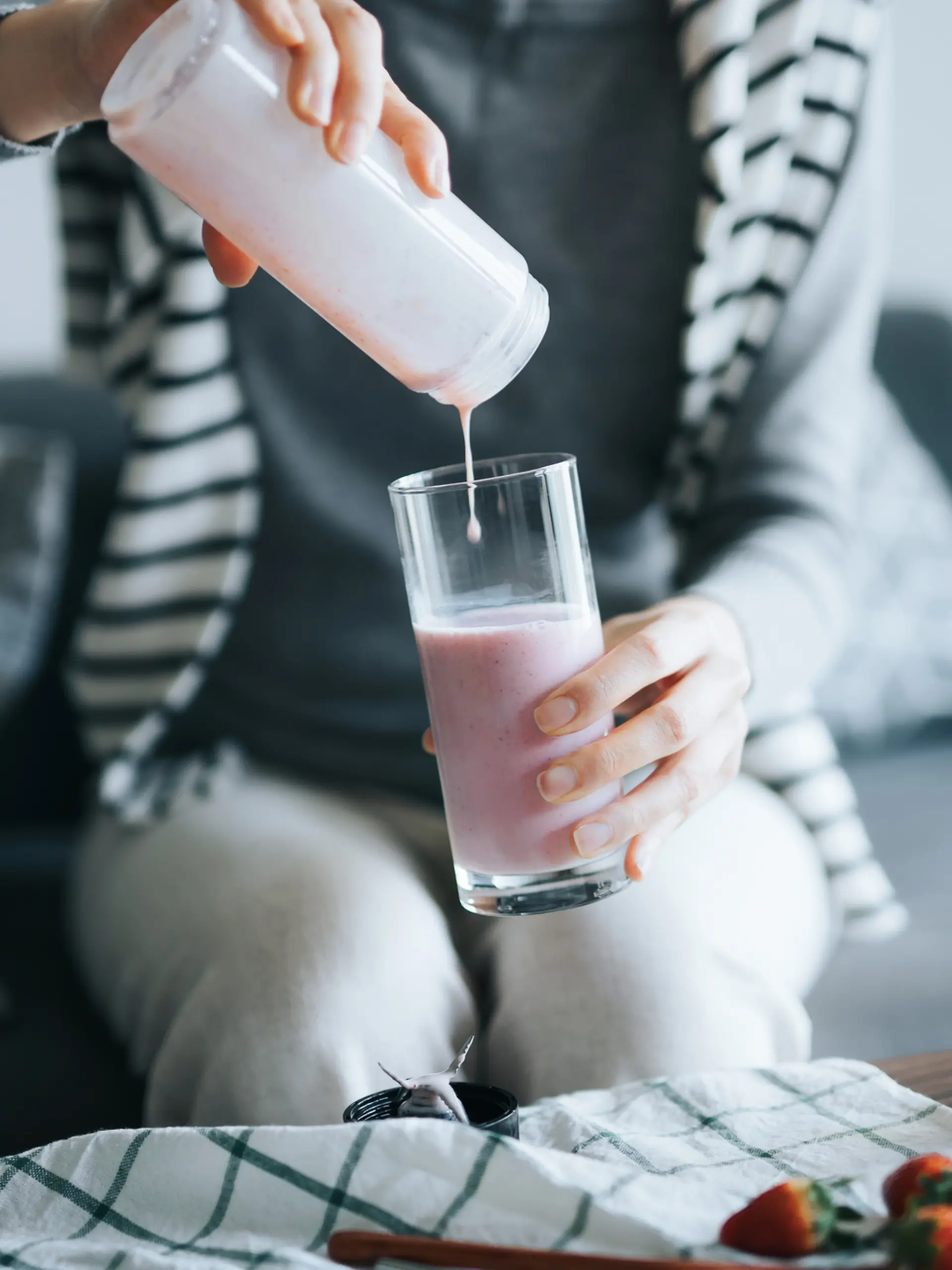 Person gießt sich einen Shake in ein Glas ein.