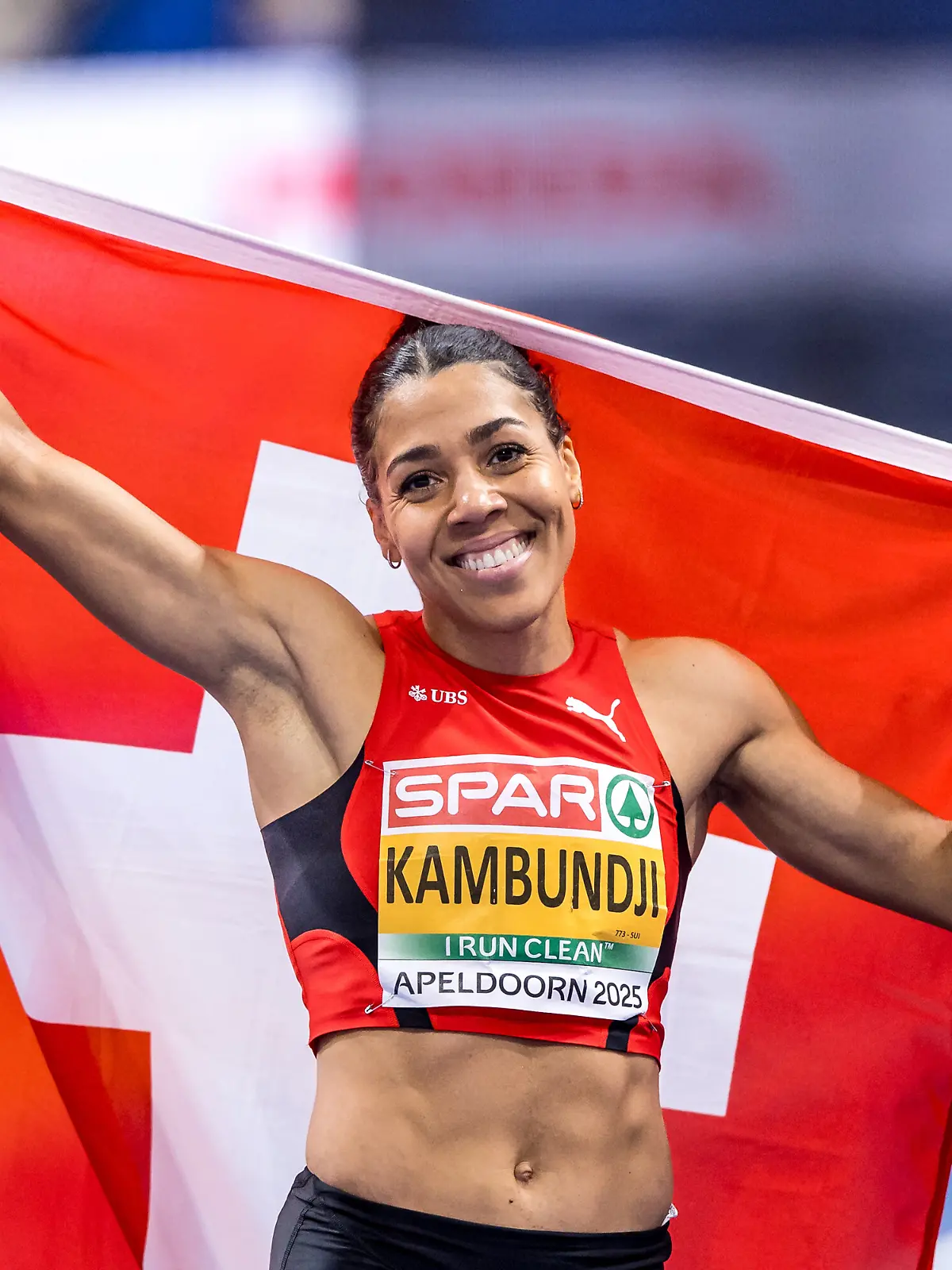 Die Schweizer Sprinterin Mujinga Kambundji posiert nach dem Finale über 60m in Apeldoorn mit ihrer Flagge.