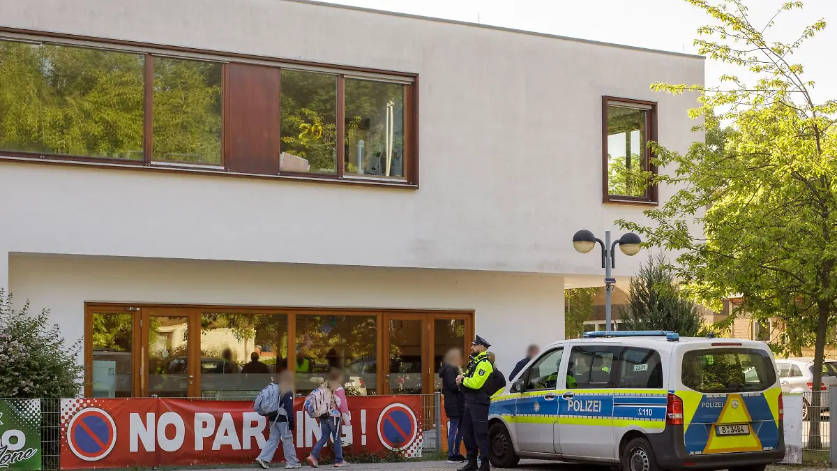 Die Polizei steht vor einer Grundschule im Berliner Bezirk Spandau, während Schüler am Morgen zur Schule kommen.