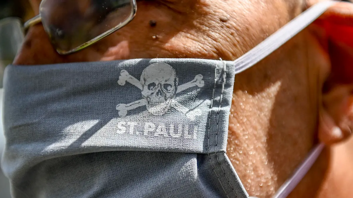 17.05.2020, Hamburg: Fußball: 2. Bundesliga, FC St. Pauli - 1. FC Nürnberg, 26. Spieltag im Millerntor-Stadion. Ein Vereinsmitarbeiter trägt eine Maske mit dem Vereinslogo. Foto: Axel Heimken/dpa - Pool/dpa - WICHTIGER HINWEIS: Gemäß den Vorgaben der DFL Deutsche Fußball Liga bzw. des DFB Deutscher Fußball-Bund ist es untersagt, in dem Stadion und/oder vom Spiel angefertigte Fotoaufnahmen in Form von Sequenzbildern und/oder videoähnlichen Fotostrecken zu verwerten bzw. verwerten zu lassen. +++ dpa-Bildfunk +++