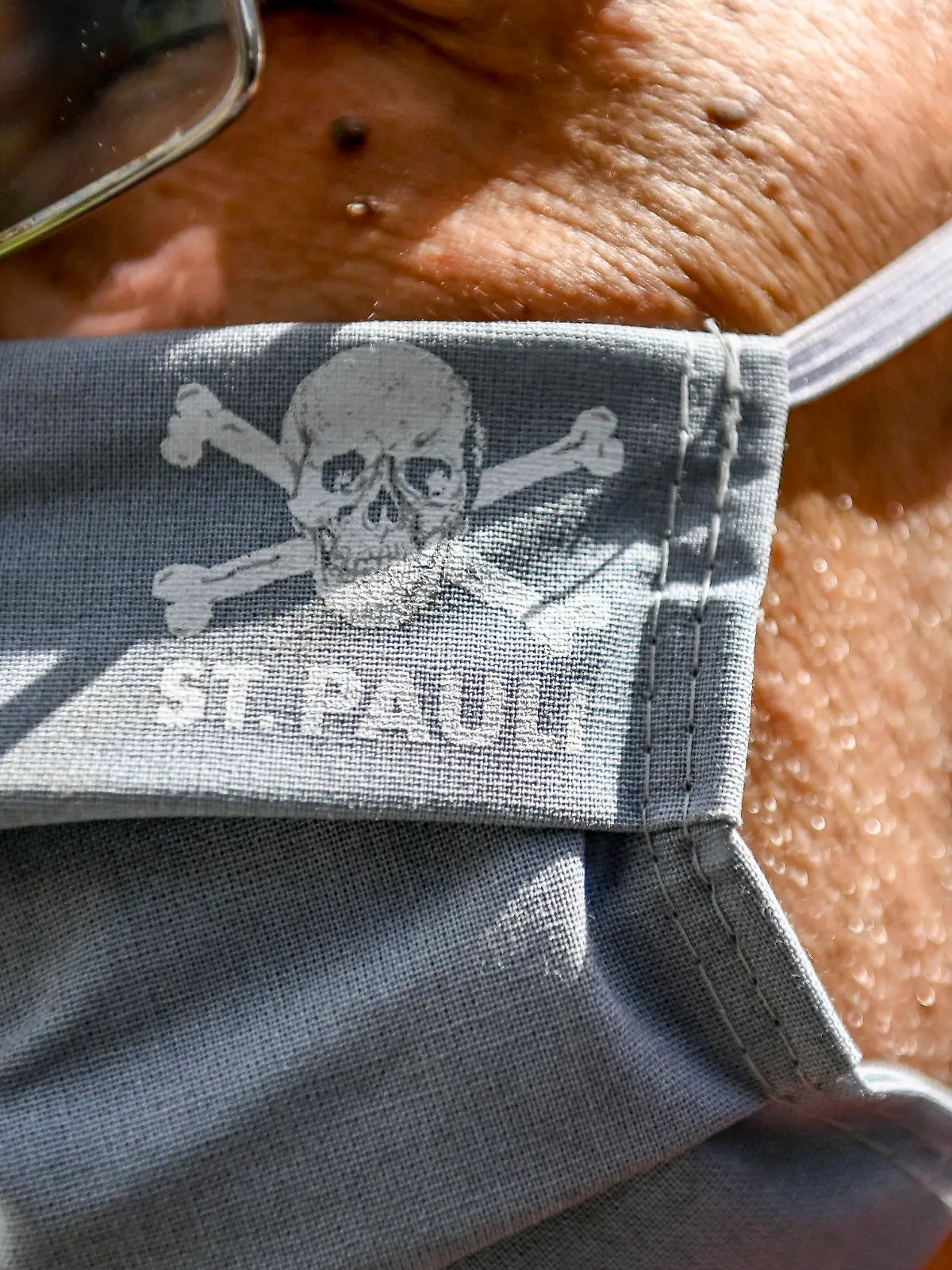 17.05.2020, Hamburg: Fußball: 2. Bundesliga, FC St. Pauli - 1. FC Nürnberg, 26. Spieltag im Millerntor-Stadion. Ein Vereinsmitarbeiter trägt eine Maske mit dem Vereinslogo. Foto: Axel Heimken/dpa - Pool/dpa - WICHTIGER HINWEIS: Gemäß den Vorgaben der DFL Deutsche Fußball Liga bzw. des DFB Deutscher Fußball-Bund ist es untersagt, in dem Stadion und/oder vom Spiel angefertigte Fotoaufnahmen in Form von Sequenzbildern und/oder videoähnlichen Fotostrecken zu verwerten bzw. verwerten zu lassen. +++ dpa-Bildfunk +++