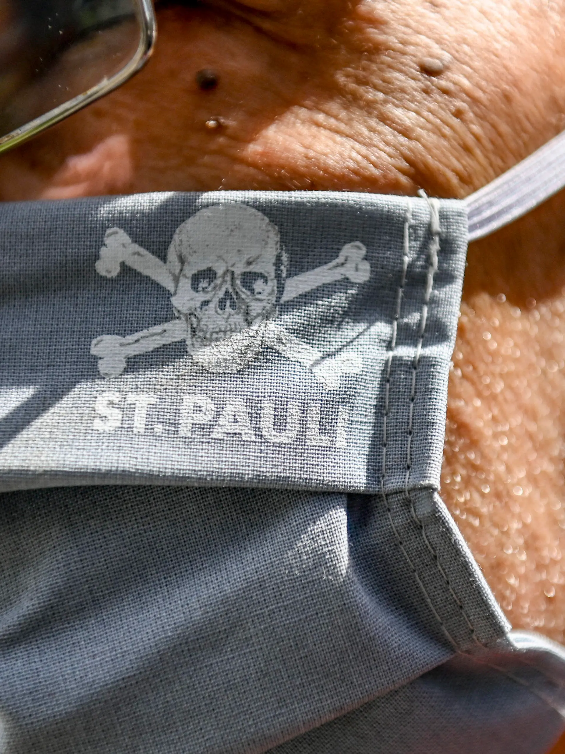 17.05.2020, Hamburg: Fußball: 2. Bundesliga, FC St. Pauli - 1. FC Nürnberg, 26. Spieltag im Millerntor-Stadion. Ein Vereinsmitarbeiter trägt eine Maske mit dem Vereinslogo. Foto: Axel Heimken/dpa - Pool/dpa - WICHTIGER HINWEIS: Gemäß den Vorgaben der DFL Deutsche Fußball Liga bzw. des DFB Deutscher Fußball-Bund ist es untersagt, in dem Stadion und/oder vom Spiel angefertigte Fotoaufnahmen in Form von Sequenzbildern und/oder videoähnlichen Fotostrecken zu verwerten bzw. verwerten zu lassen. +++ dpa-Bildfunk +++