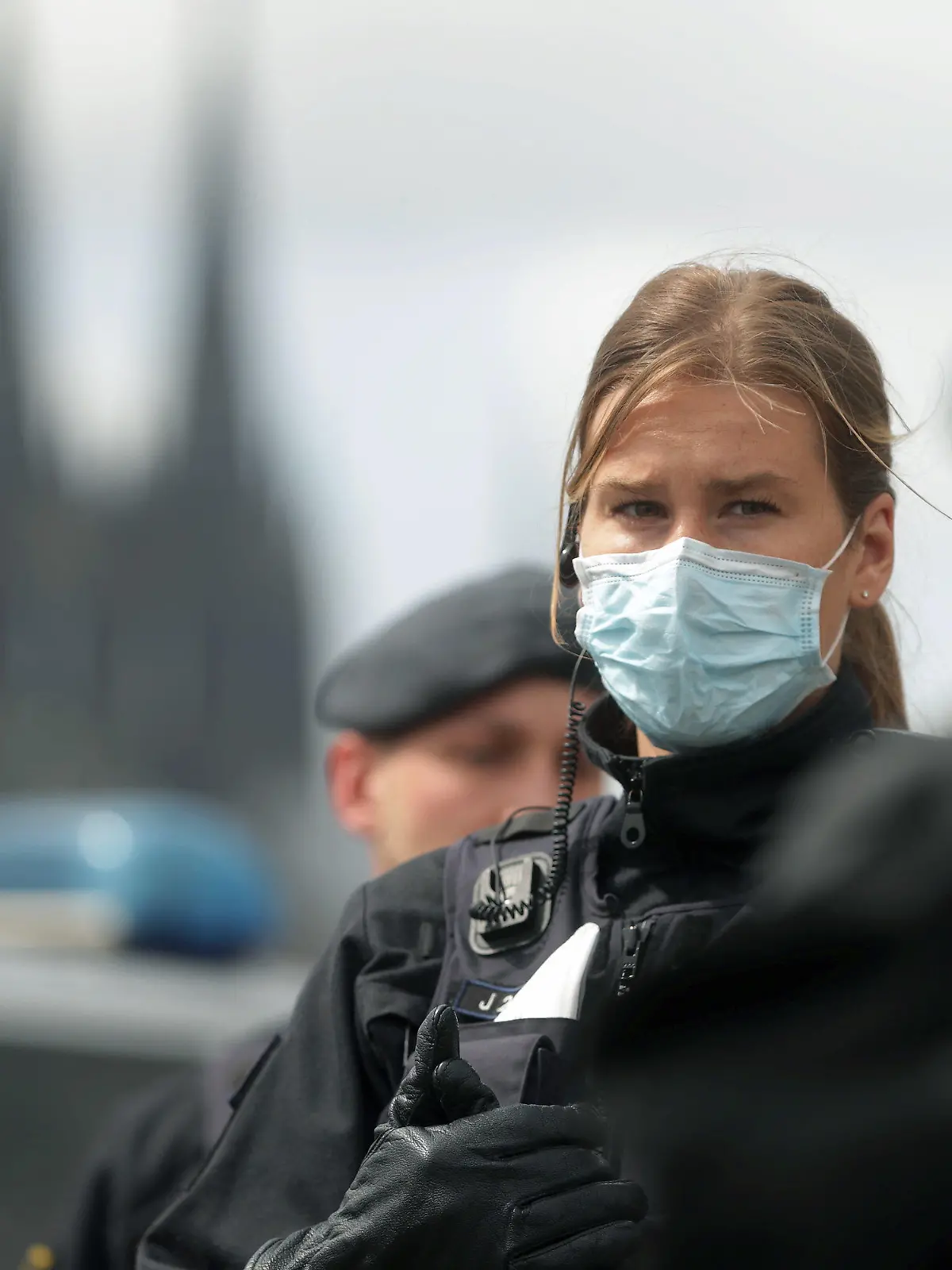 23.05.2020, Nordrhein-Westfalen, Köln: Bei einer Demonstration gegen Corona-Beschränkungen steht eine Polizistin mit medizinischem Mundschutz. Im Hintergrund der Kölner Dom. Foto: David Young/dpa +++ dpa-Bildfunk +++