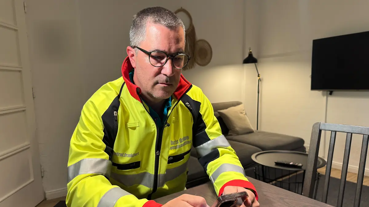Deutschlands bekanntester Notfallsanitäter Chris Grüne sitzt an einem Tisch und liest einen Artikel über den Messerangriff am Hambuger Hauptbahnhof