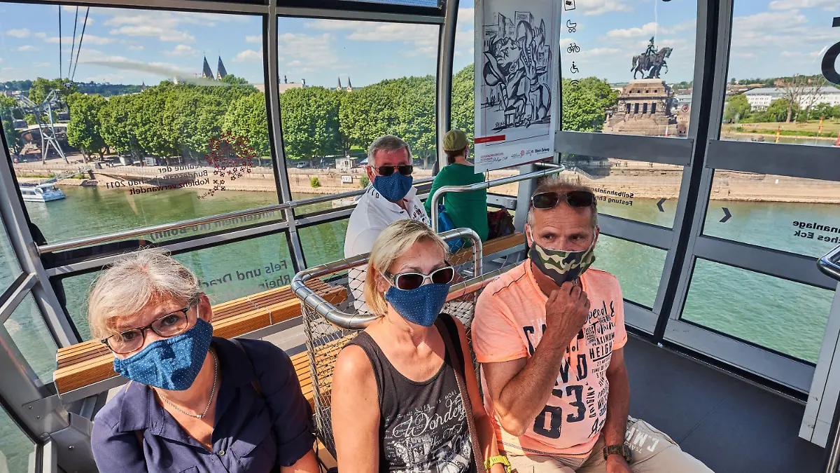 29.05.2020, Rheinland-Pfalz, Koblenz: Eine Gruppe von Touristen aus Aachen sitzt mit Mund-Nase-Schutzmasken in einer Gondel der Seilbahn, die zwischen dem Deutschen Eck und der Festung Ehrenbreitstein den Rhein überquert. Nach mehr als zweimonatiger Zwangspause wegen des hochansteckenden Corona-Virus ist die Touristenattraktion jetzt wieder in Betrieb. Foto: Thomas Frey/dpa +++ dpa-Bildfunk +++