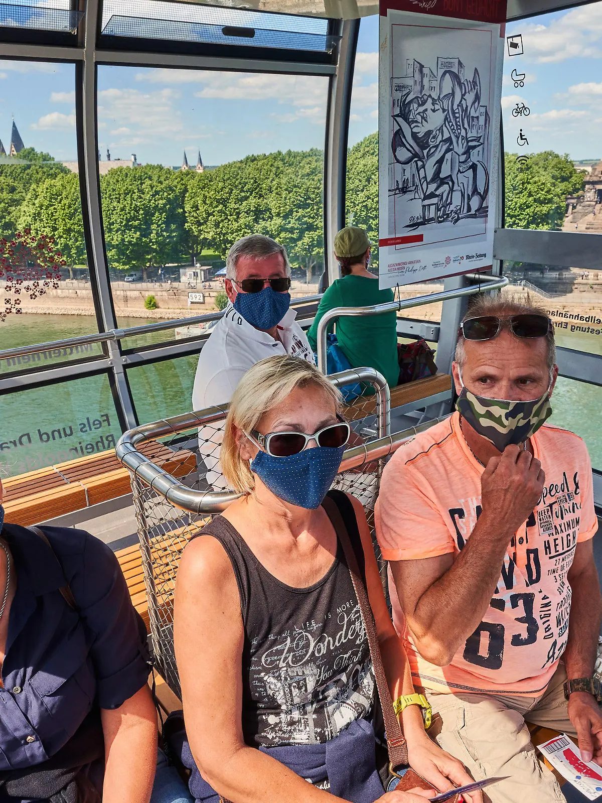 29.05.2020, Rheinland-Pfalz, Koblenz: Eine Gruppe von Touristen aus Aachen sitzt mit Mund-Nase-Schutzmasken in einer Gondel der Seilbahn, die zwischen dem Deutschen Eck und der Festung Ehrenbreitstein den Rhein überquert. Nach mehr als zweimonatiger Zwangspause wegen des hochansteckenden Corona-Virus ist die Touristenattraktion jetzt wieder in Betrieb. Foto: Thomas Frey/dpa +++ dpa-Bildfunk +++