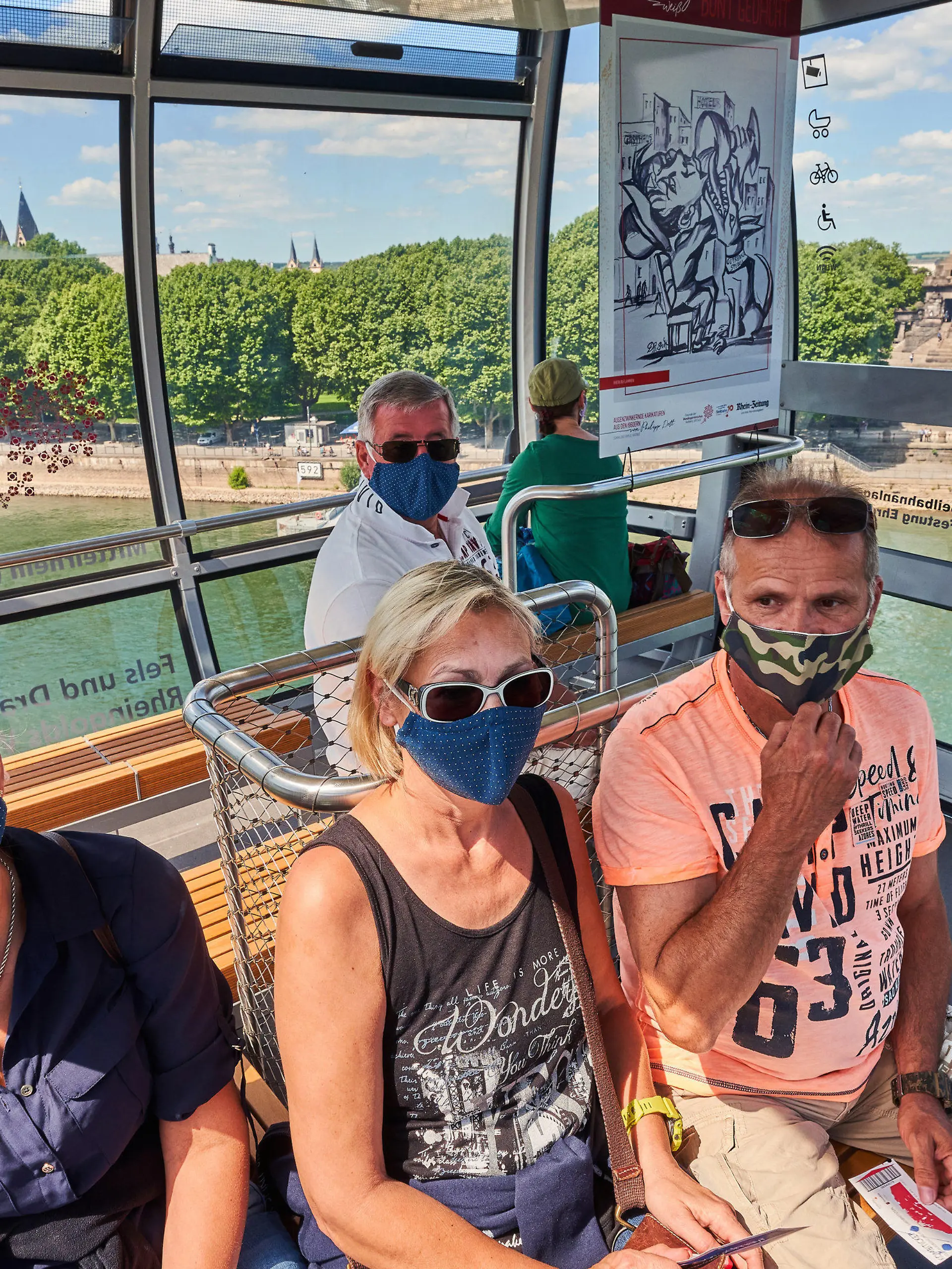 29.05.2020, Rheinland-Pfalz, Koblenz: Eine Gruppe von Touristen aus Aachen sitzt mit Mund-Nase-Schutzmasken in einer Gondel der Seilbahn, die zwischen dem Deutschen Eck und der Festung Ehrenbreitstein den Rhein überquert. Nach mehr als zweimonatiger Zwangspause wegen des hochansteckenden Corona-Virus ist die Touristenattraktion jetzt wieder in Betrieb. Foto: Thomas Frey/dpa +++ dpa-Bildfunk +++