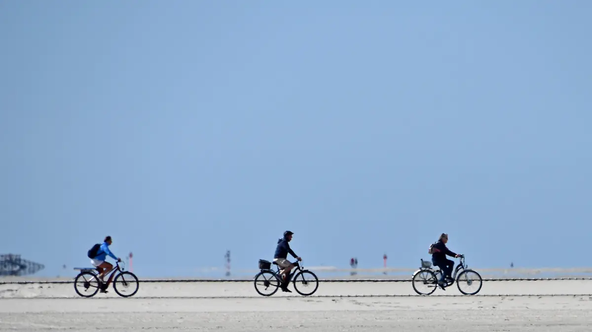 29.05.2020, Schleswig-Holstein, St.Peter-Ording: Radfahrer fahren bei blauem Himmel über den Nordseestrand. Für die nordfriesischen Inseln und Halligen der Nordsee sowie für St. Peter-Ording gilt über Pfingsten vom 30. Mai 6 Uhr bis 1. Juni 20 Uhr ein Betretungsverbot für Tagesgäste. Foto: Carsten Rehder/dpa +++ dpa-Bildfunk +++
