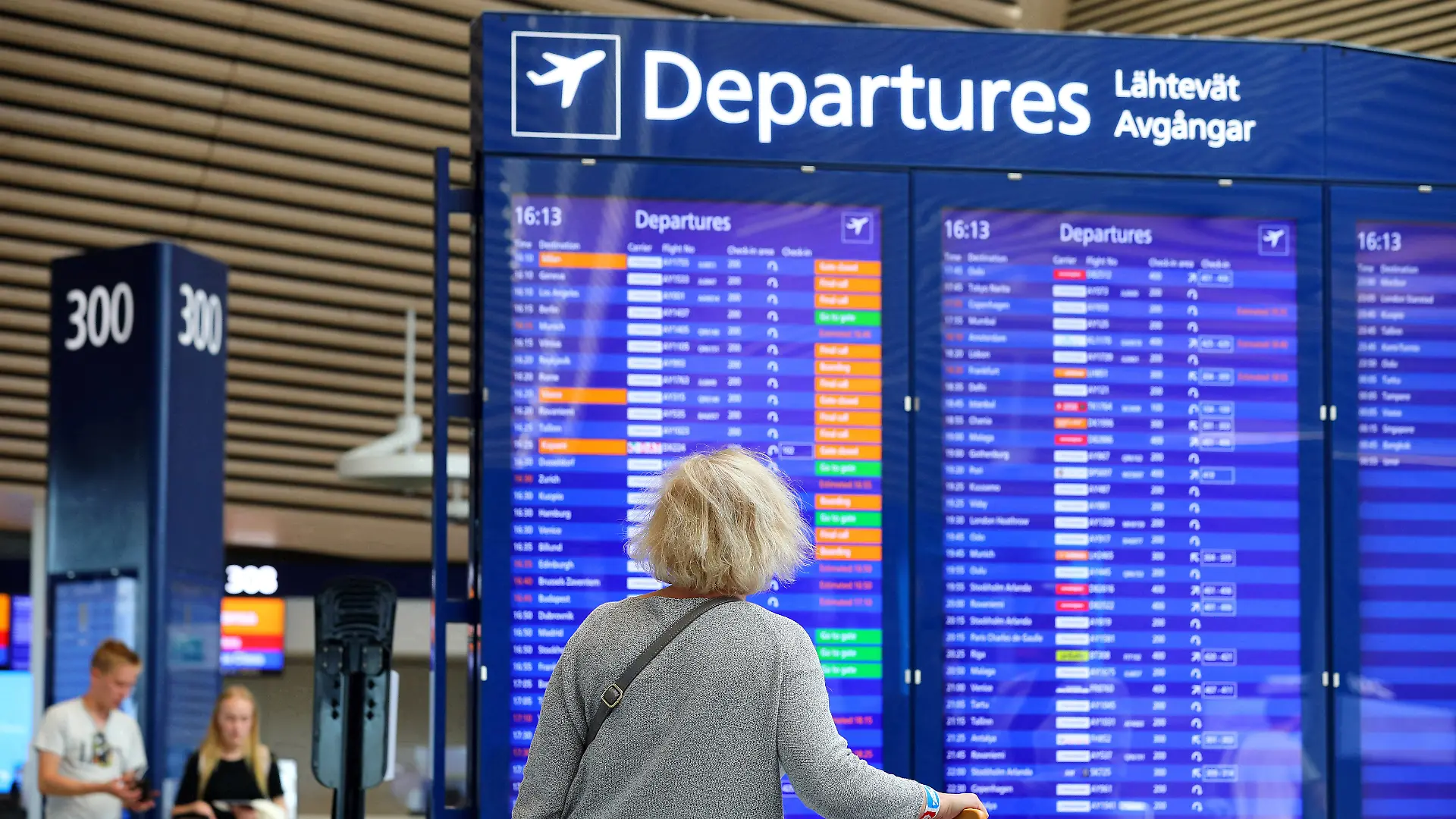 Eine Frau steht vor einer Anzeigetafel am Flughafen.
