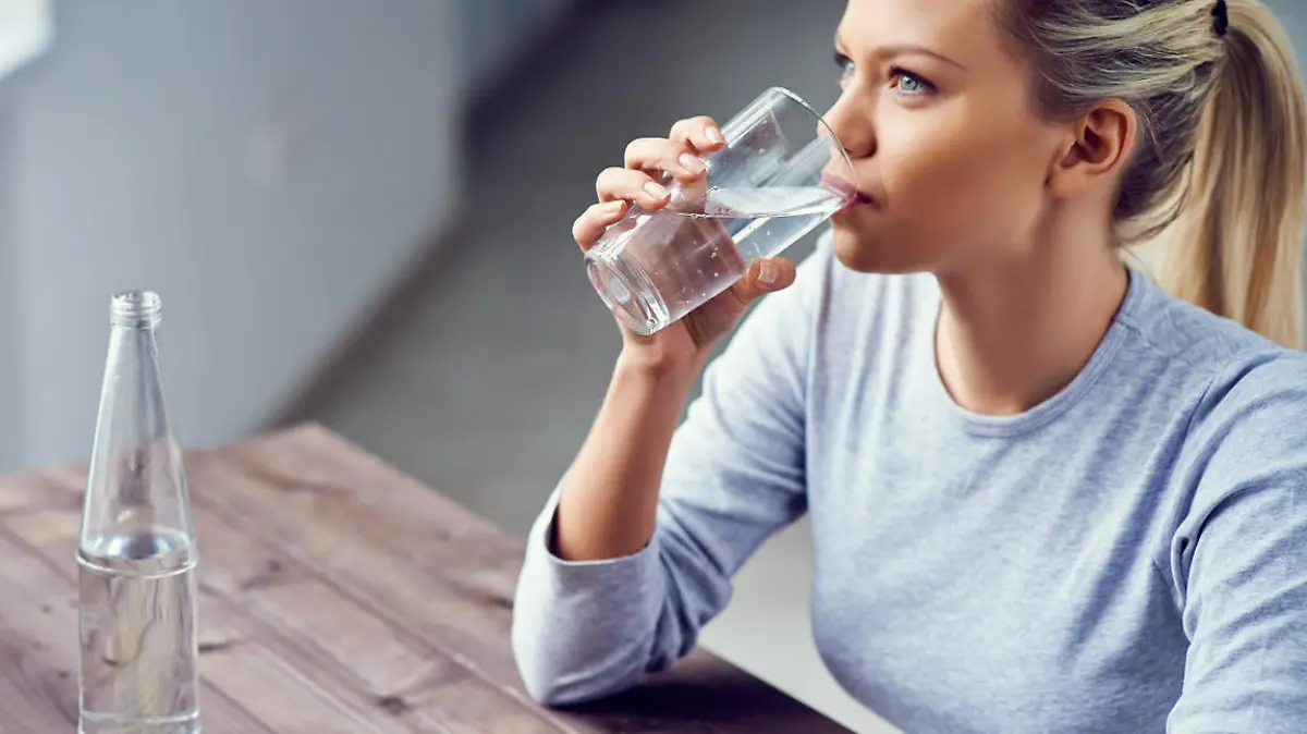 Junge Frau trinkt morgens Wasser