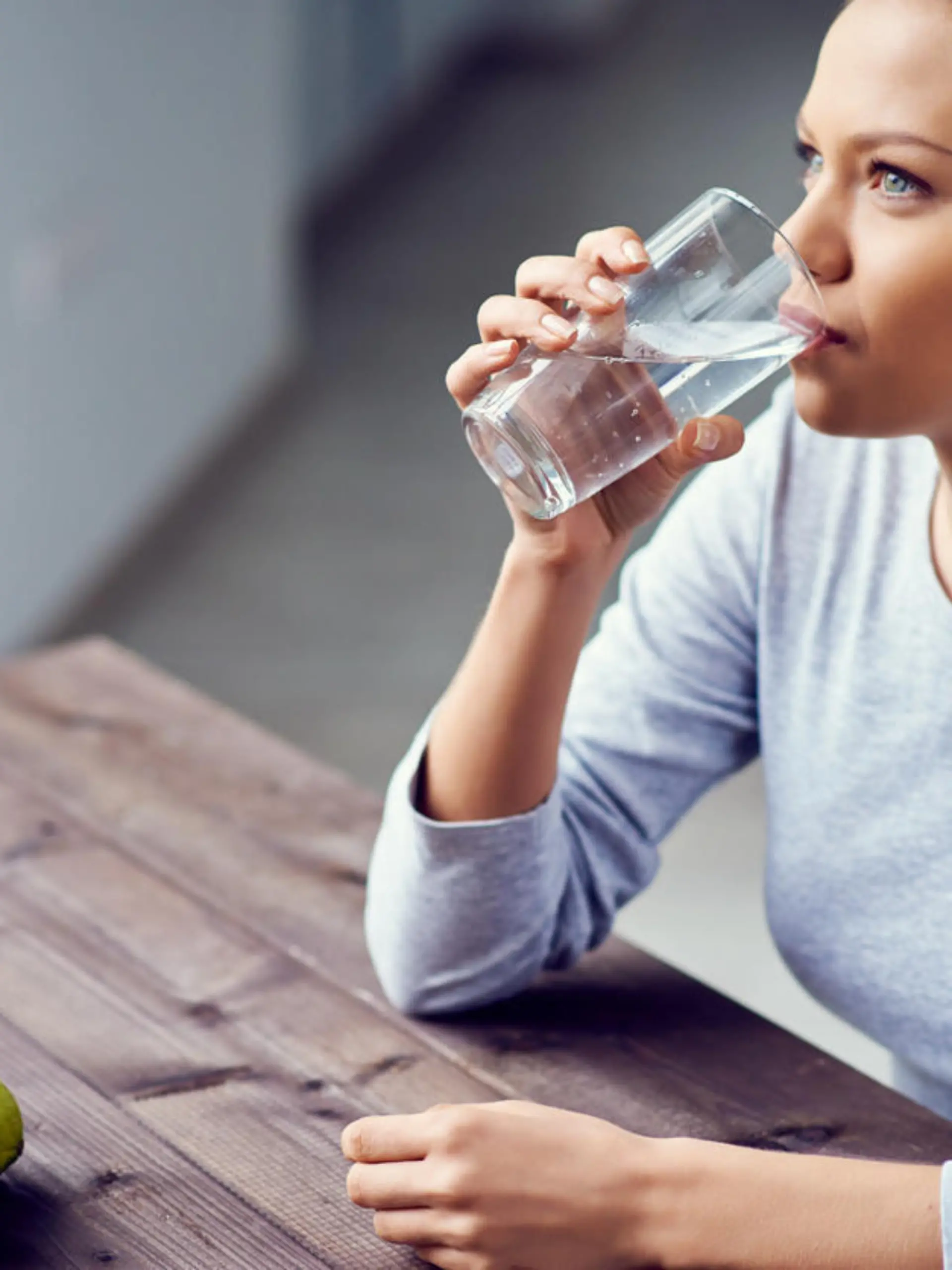 Junge Frau trinkt morgens Wasser