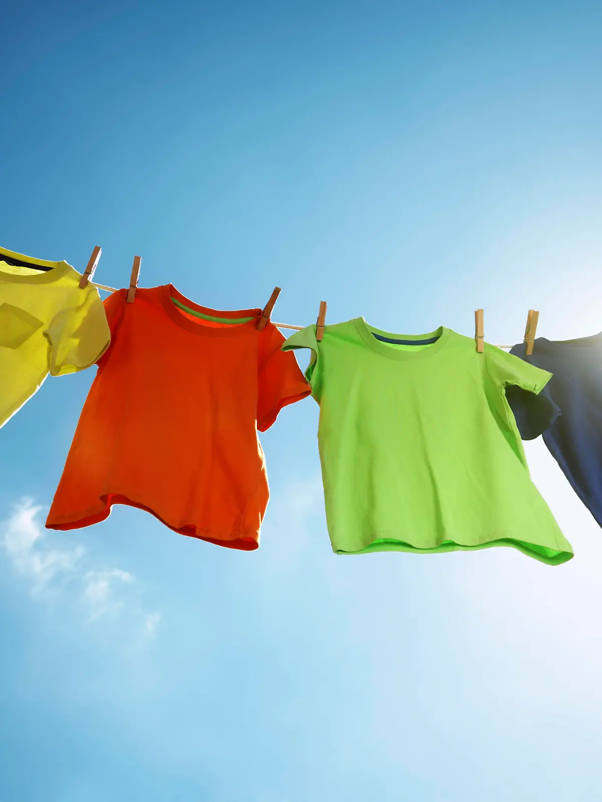 Wäsche, T-shirts hanging on a clothesline in front of blue sky and sun