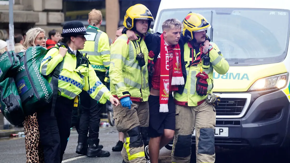 Rettungskräfte stützen einen offenbar verletzten Liverpool-Fan.