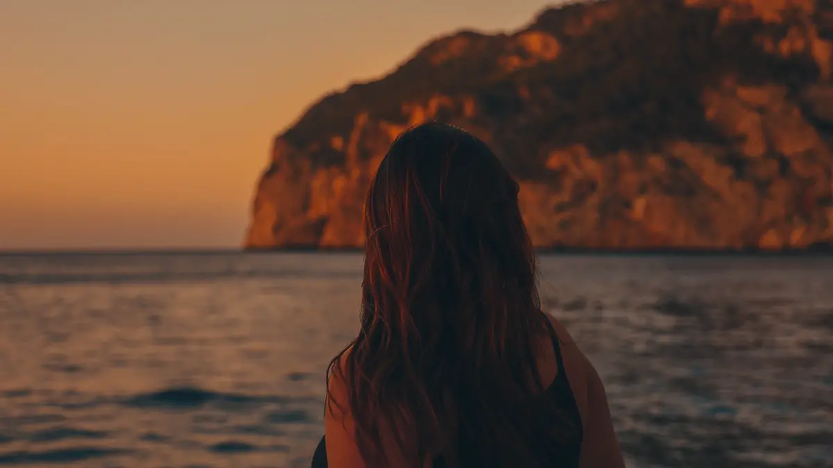 Frau auf spanischer Insel schaut aufs Meer.