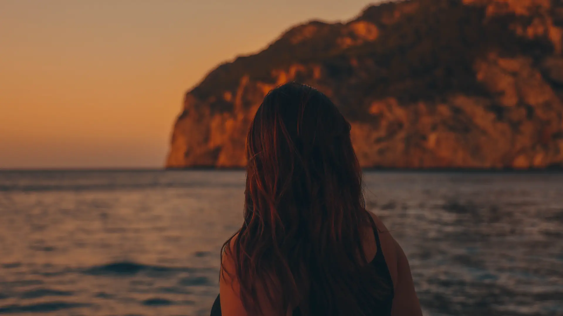 Frau auf spanischer Insel schaut aufs Meer.