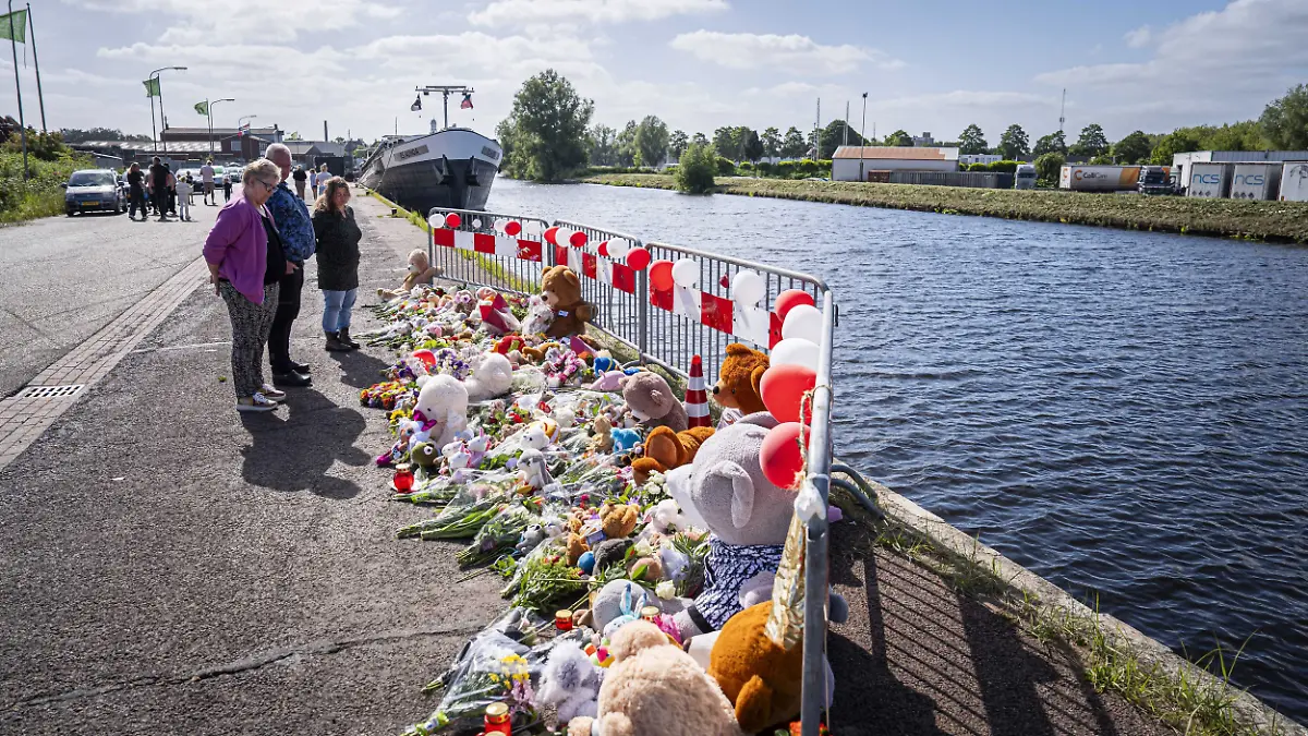 dpatopbilder - 21.05.2025, Niederlande, Winschoten: Menschen stehen an einer Gedenkstätte vor Blumen und Stofftieren. Nach tagelanger Suche gibt es Gewissheit: Die beiden im Nordosten der Niederlande vermissten Kinder sind tot. Jeffrey und seine Schwester Emma wurden im Auto ihres Vaters in einem Kanal gefunden. Foto: Jaspar Moulijn/ANP/dpa +++ dpa-Bildfunk +++