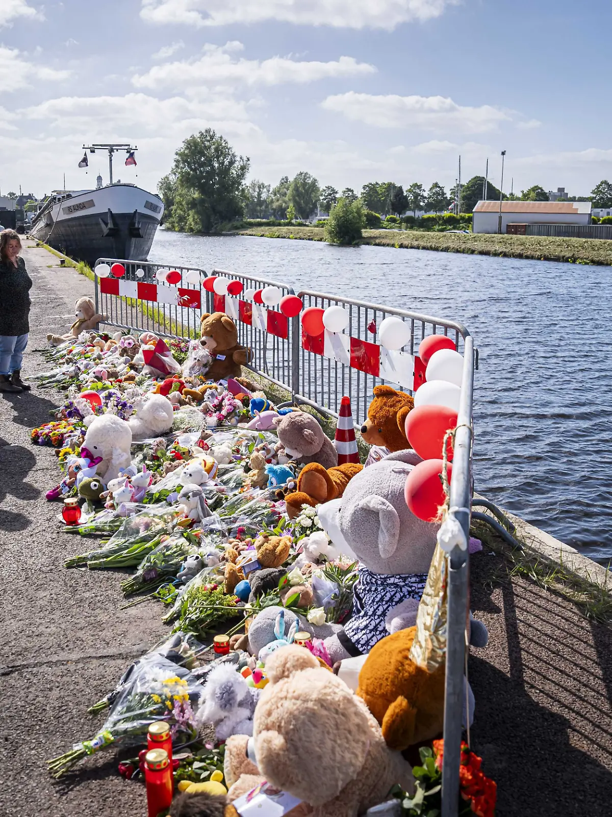 dpatopbilder - 21.05.2025, Niederlande, Winschoten: Menschen stehen an einer Gedenkstätte vor Blumen und Stofftieren. Nach tagelanger Suche gibt es Gewissheit: Die beiden im Nordosten der Niederlande vermissten Kinder sind tot. Jeffrey und seine Schwester Emma wurden im Auto ihres Vaters in einem Kanal gefunden. Foto: Jaspar Moulijn/ANP/dpa +++ dpa-Bildfunk +++