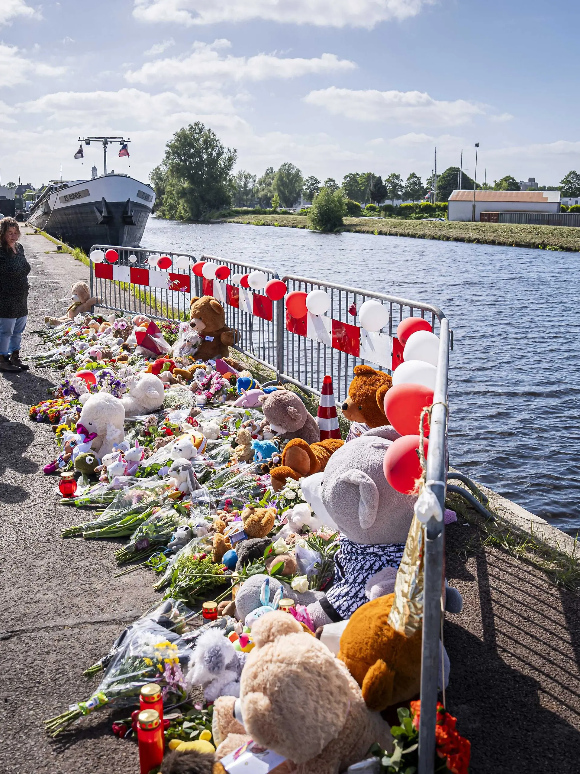 dpatopbilder - 21.05.2025, Niederlande, Winschoten: Menschen stehen an einer Gedenkstätte vor Blumen und Stofftieren. Nach tagelanger Suche gibt es Gewissheit: Die beiden im Nordosten der Niederlande vermissten Kinder sind tot. Jeffrey und seine Schwester Emma wurden im Auto ihres Vaters in einem Kanal gefunden. Foto: Jaspar Moulijn/ANP/dpa +++ dpa-Bildfunk +++