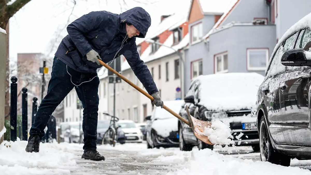 10.03.2023, Bremen: Ein Anwohner befreit den Fußgängerweg von Schnee. Das Wetter bleibt in den kommenden Tagen durchwachsen, jedoch sollen die Temperaturen steigen. Foto: Sina Schuldt/dpa +++ dpa-Bildfunk +++