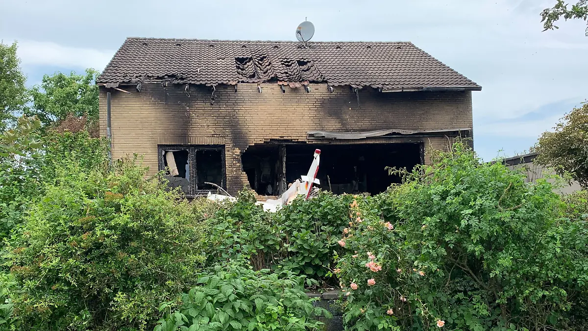 Die Feuerwehr arbeitet an der Absturzstelle, nachdem ein Flugzeug in ein Wohnhaus gestürzt ist.
