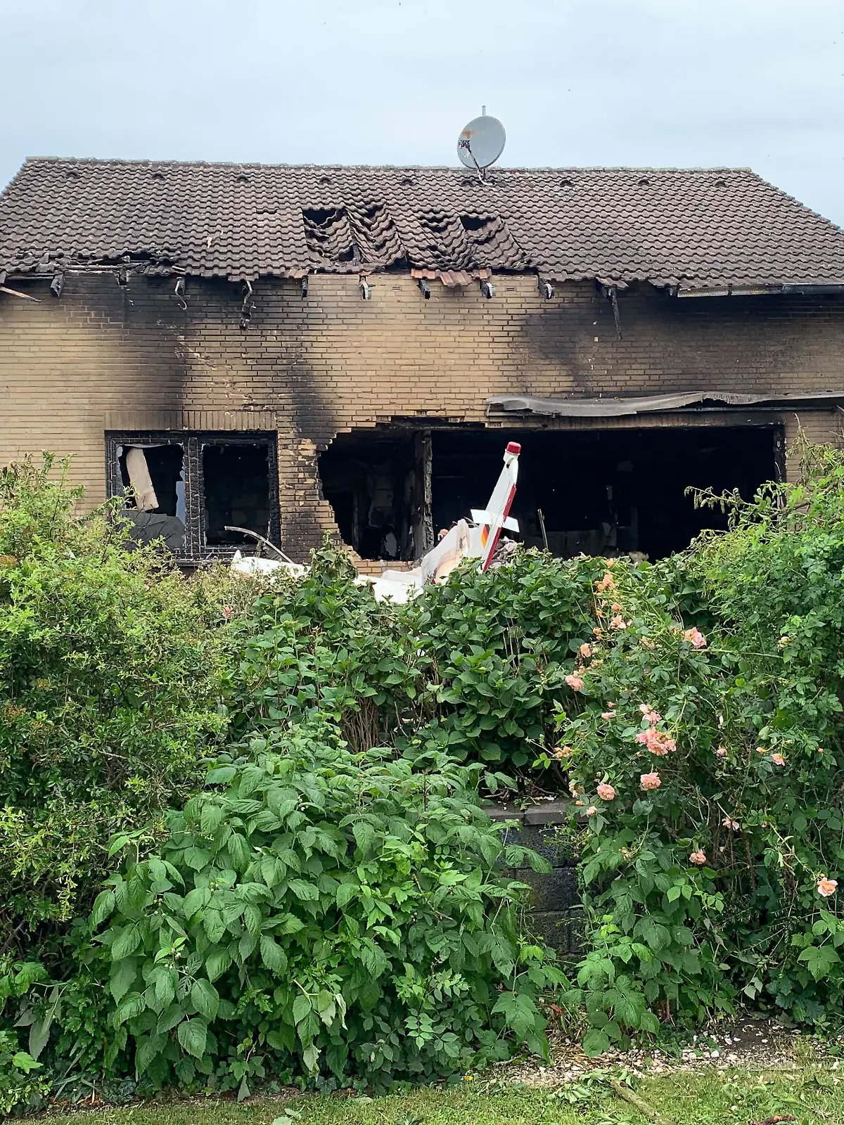Die Feuerwehr arbeitet an der Absturzstelle, nachdem ein Flugzeug in ein Wohnhaus gestürzt ist.