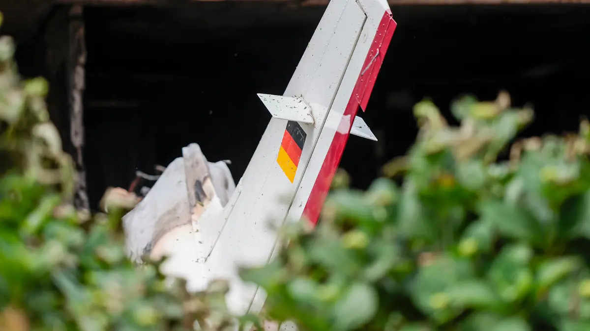 Trümmer eines Kleinflugzeugs liegen auf der Terrasse und im Garten eines Wohnhauses.