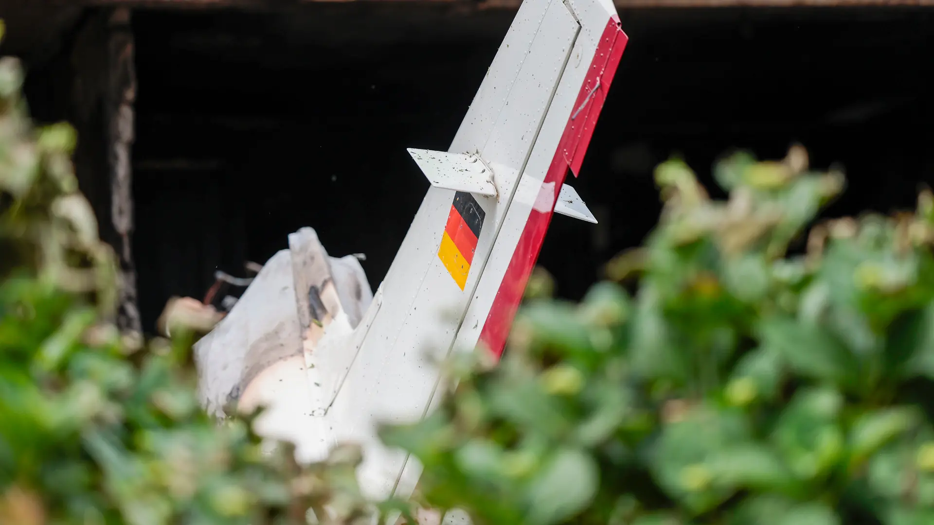 Trümmer eines Kleinflugzeugs liegen auf der Terrasse und im Garten eines Wohnhauses.