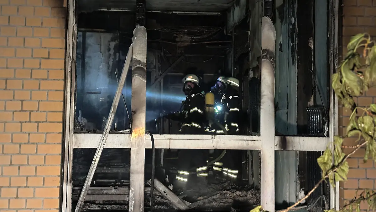  Feuerwehrleute mit Atemschutzgerät arbeiten in einem ausgebrannten Raum im Erdgeschoß im Marienkrankenhaus im Hamburger Stadtteil Hohenfelde.