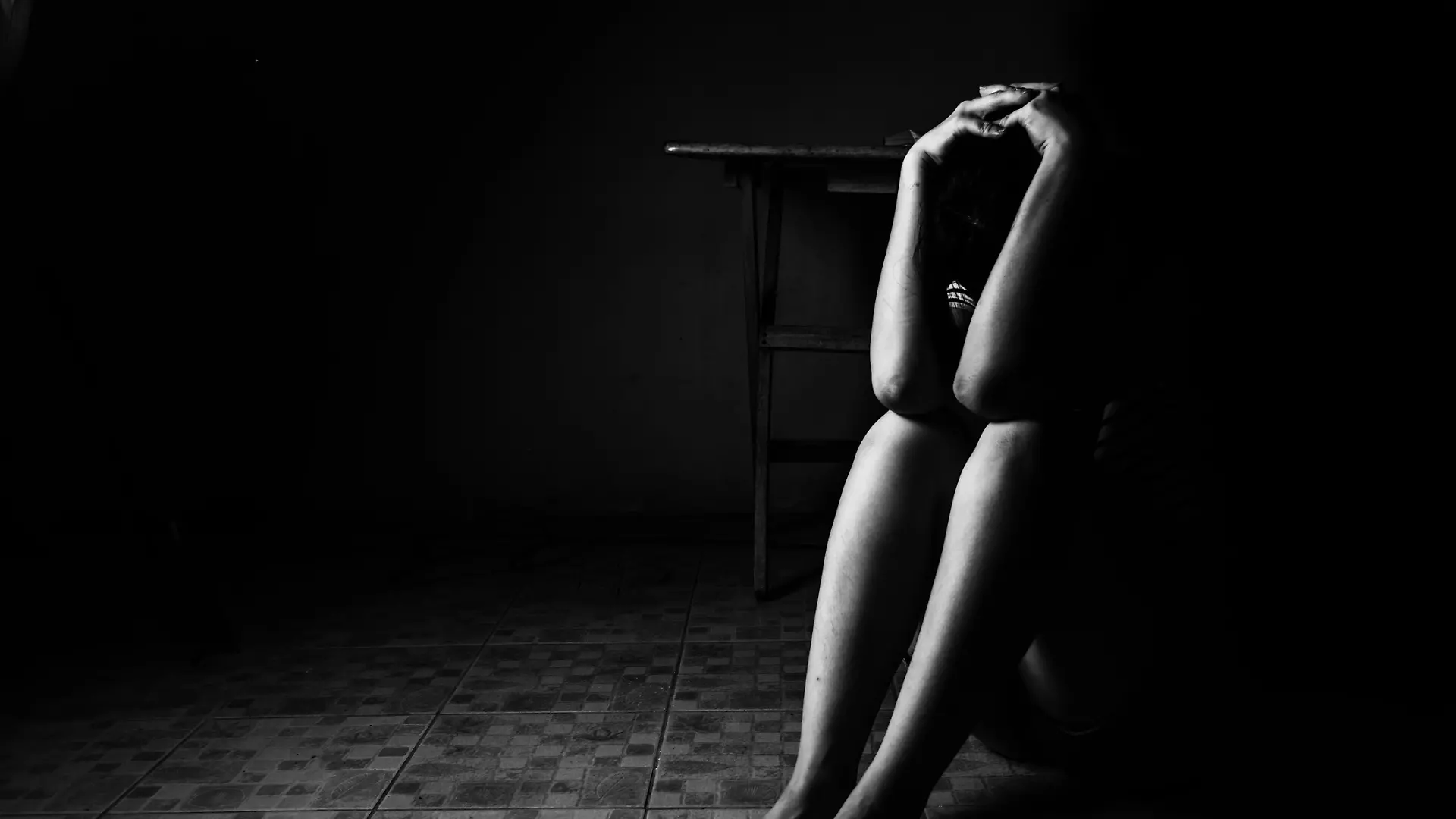 a woman sitting on ground with arm around lower head, sexual violence , sexual abuse, human trafficking concept with shadow edge in white tone