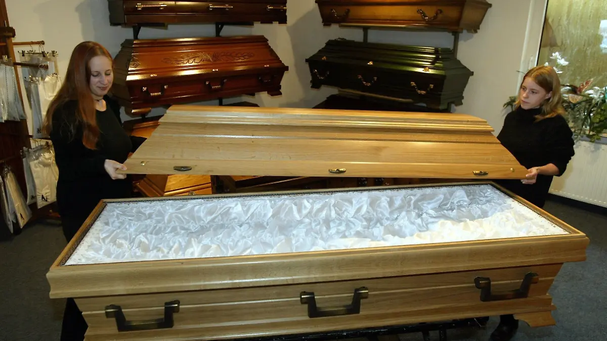 Die ersten Bestatter-Azubis Niedersachsen, Jessica Keuneke (l) und Katrin Scholz, heben am 28.8.2003 im Schauraum des Bestattungsinstituts Bamberg in Großburgwedel bei Hannover nach dem Ausschlagen des Sarges den Deckel auf. Zwischen Särgen, Bahren und Leichentüchern lernen die 17-jährige Katrin und die 21-jährige Jessica für den Trauerfall: Sie sind Niedersachsens erste Auszubildende zur Bestattungsfachkraft.
