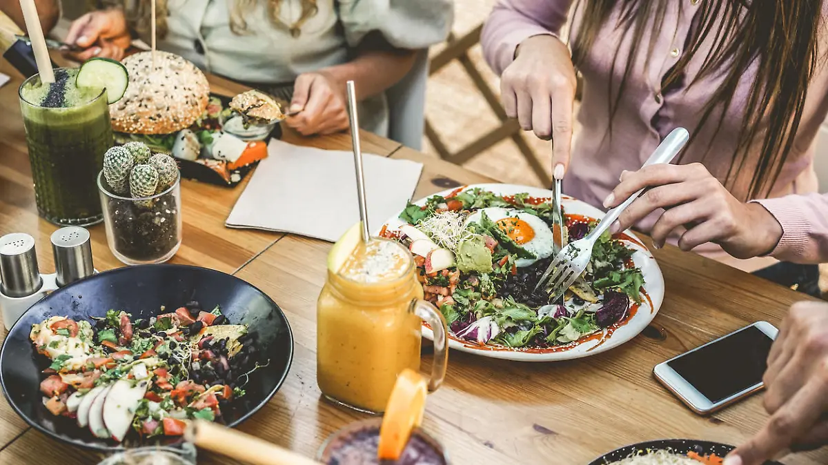 Hands view of young people eating brunch and drinking smoothies bowl with ecological straws in plastic free restaurant - Healthy lifestyle, food trends concept - Focus on top fork dish
