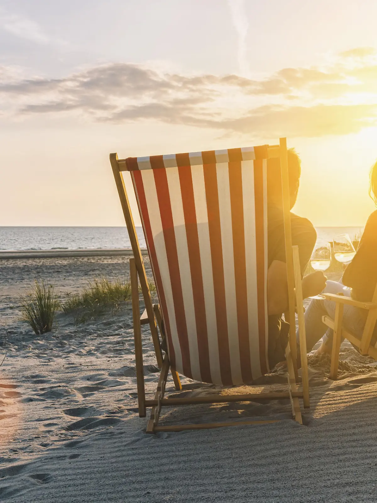 Paar trinkt Wein am Strand im Urlaub.