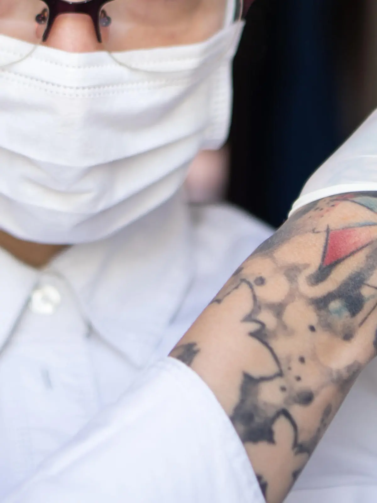Tätowierte Frau mit Handschuhen und Maske