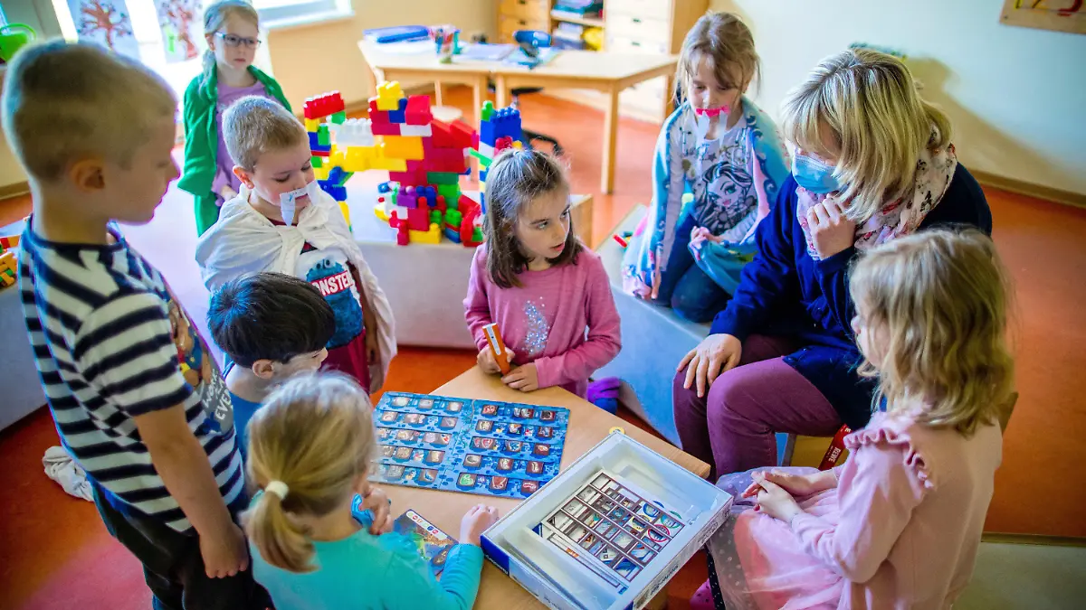20.05.2020, Mecklenburg-Vorpommern, Schwerin: Erzieherin Katrin Dorn spielt mit den Kinder der Vorschulgruppe in der Kindertagesstätte "Anne Frank". In den Kitas von Mecklenburg-Vorpommern zieht langsam wieder Normalität ein. Als erste durften die Mädchen und Jungen der Vorschulgruppen ab dem 18.05.2020 wieder regulär in den Kindergarten gehen. Ab dem 25.05.2020 stehen die Krippen und Kindergärten dann wieder allen offen. Foto: Jens Büttner/dpa-Zentralbild/dpa - ACHTUNG: Nur zur redaktionellen Verwendung im Zusammenhang mit der aktuellen Berichterstattung. +++ dpa-Bildfunk +++