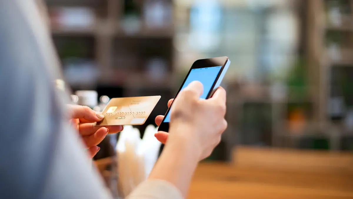Frau hält für Online-Banking Kreditkarte und Smartphone in der Hand