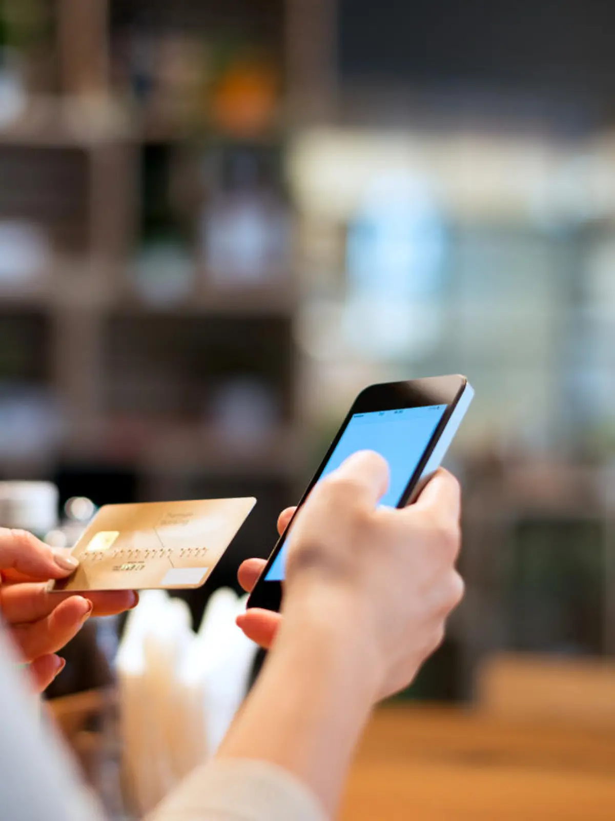 Frau hält für Online-Banking Kreditkarte und Smartphone in der Hand